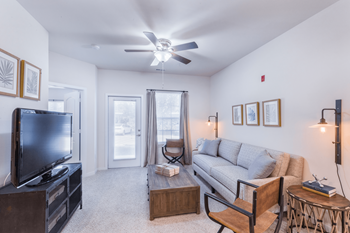 A living room with a television, couch, and a ceiling fan.